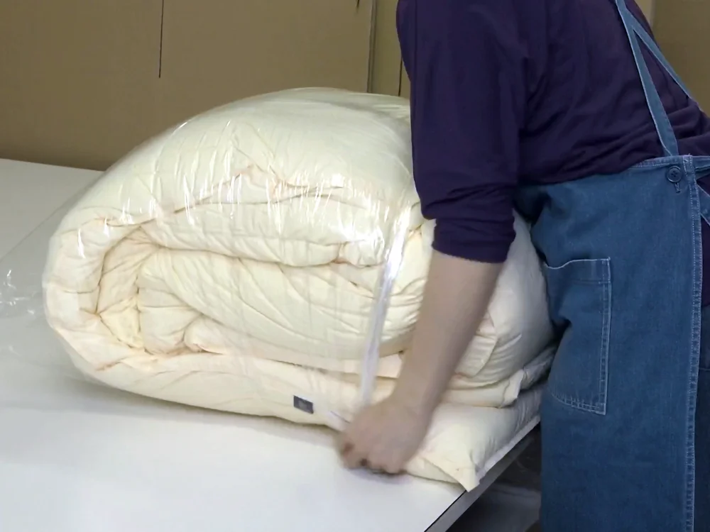 羽毛ふとんをビニール袋へ入れる梱包工程